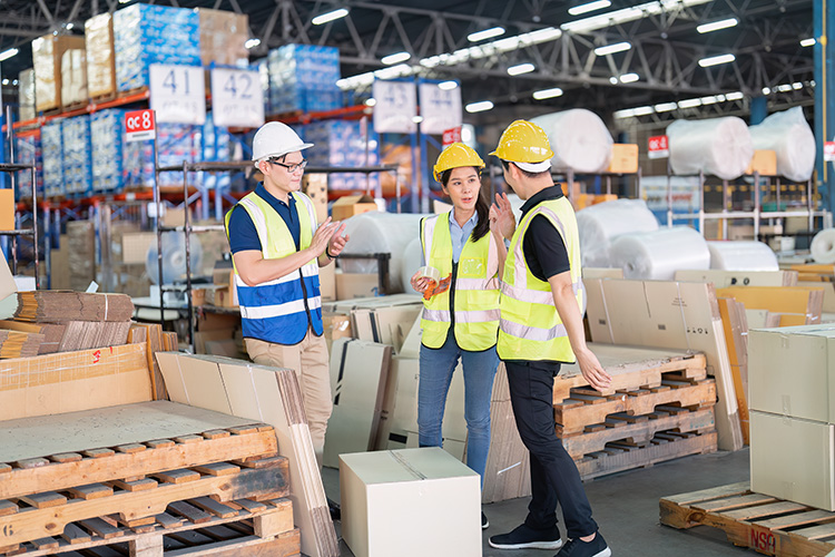 Staff in large storage warehouse together packing goods and carr